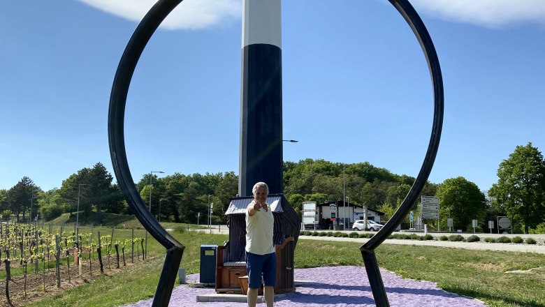 Key experience Maissau, © Weinstraße Weinviertel A man stands behind a large key shape in Maissau, with a sign for the Wine Road Weinviertel in the background.