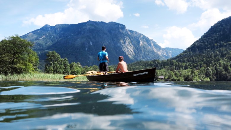 Fisherman at the lake, © Weinfranz.at Two people in a boat on a lake, surrounded by mountains and trees.