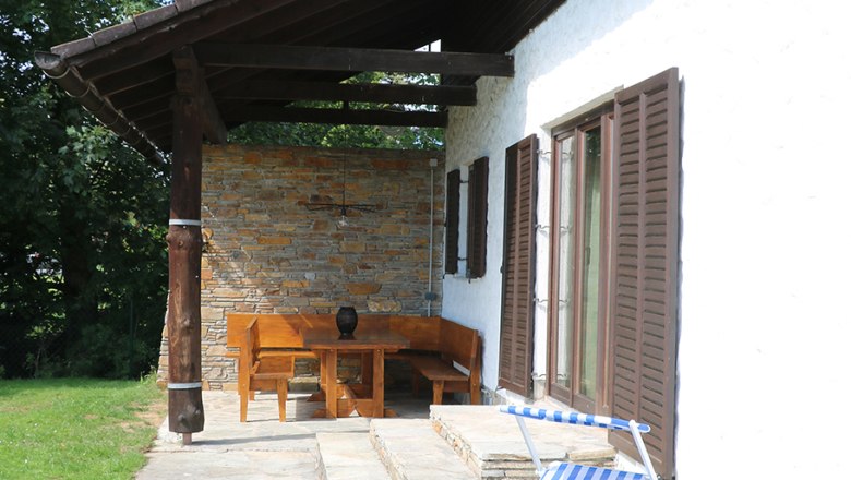 Terrace with lounger, © Pamela Hniliczka Terrace with lounger and wooden furniture next to a house with a shingle roof.