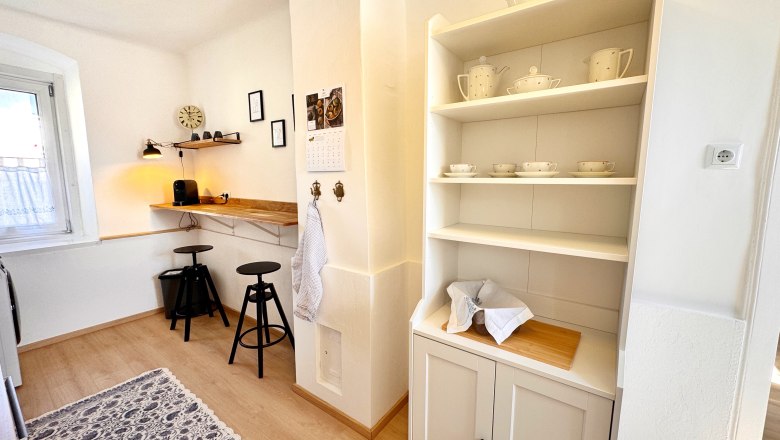 Kitchen, © Christoph Menhofer Bright kitchen with shelving, bar stools and coffee machine.