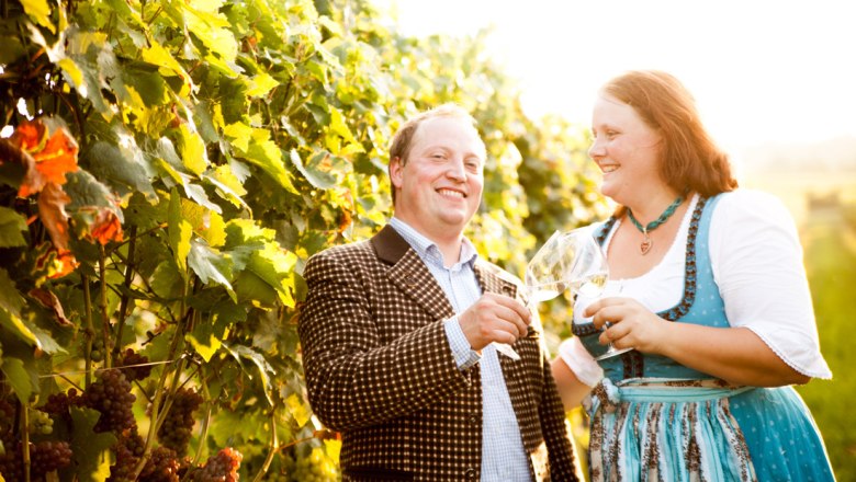 Josef and Sabrina Dürauer, © Winzerhof Dürauer, Christoph Aigner A man and a woman clink glasses in a vineyard.