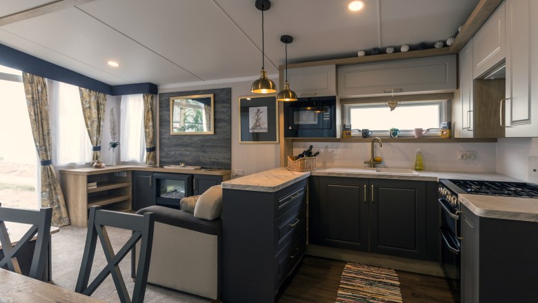 Kitchen, © Leopold Pluschkowitz Modern kitchen with dark cupboards, stove, sink and hanging lamps.