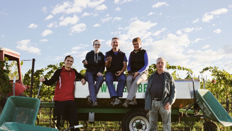 Winegrowing family, © Christoph Wurst A family poses on a tractor trailer in a vineyard.