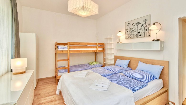 Top 2 - Bedroom, © VP FeWo OG Bedroom with double bed and bunk bed, bright furnishings.