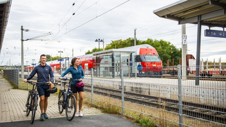 Station, © Weinviertel Tourismus GmbH / POV / Robert Herbst Two people with bicycles at Retz station, an ÖBB train in the background.