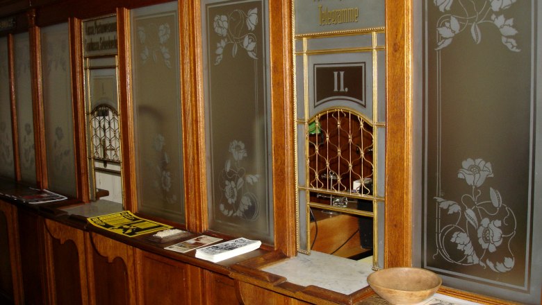 Küb post office counter, © Marktgemeinde Payerbach Historic post office counter with wooden paneling and glass windows.