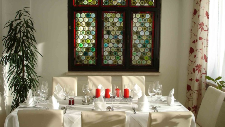 Hotel Stadt Melk, © Hotel Stadt Melk An elegantly laid table in front of a colorful glass window in a hotel.