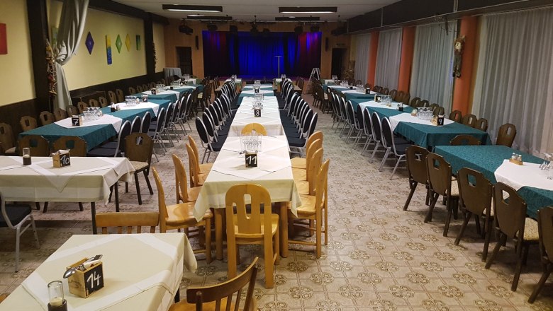 Event hall Wirtshausbühne Bernhart, © Wirtshausbühne Bernhart An empty event hall with set tables and a stage in the background.
