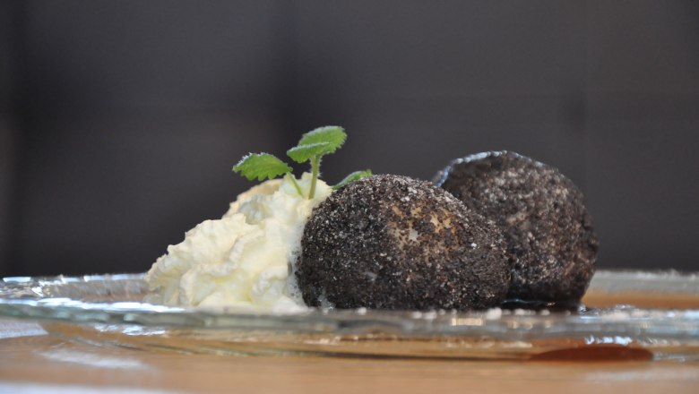 Poppy seed dumplings, © Café Pension Kristall Two poppy seed dumplings with cream and mint leaves on a glass plate.