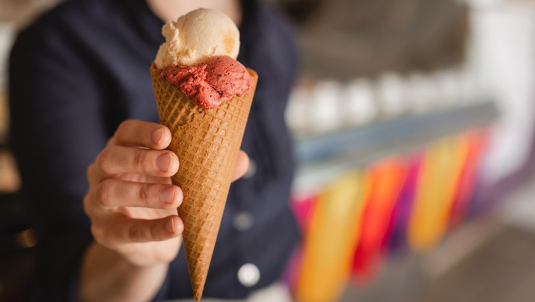 In-house ice cream parlor with a view of the monastery, © Niederösterreich Werbung/Daniela Führer Person holding an ice cream cone with two scoops of ice cream.