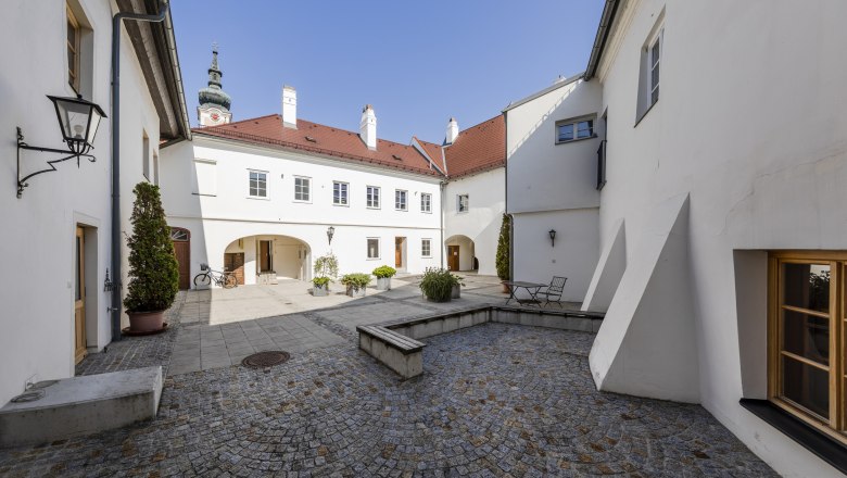 FineArtGallerie Traismauer exterior, © FineArtGallerie Inner courtyard of the TDR-FineArtGallery in Traismauer with cobblestones and white buildings.