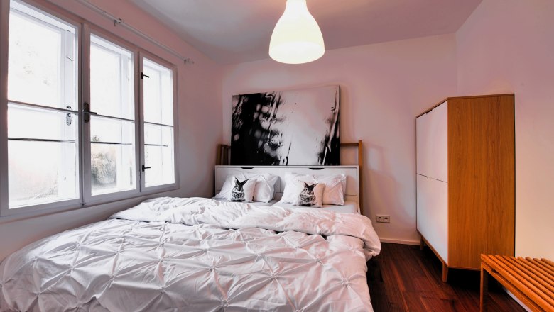 Bedroom Top 3, © Daniela Sinadinoska Modern bedroom with large bed, white bed linen and wooden wardrobe.
