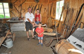 Hausstein Mountain Farm Museum, © zVg Family in a traditional wooden hut with old farming equipment.