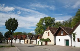 Wine cellar lane Jetzelsdorf, © Andreas Sedlmayer Row of traditional wine cellars in Jetzelsdorf under a blue sky.