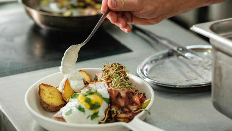 Wine.restaurant Neustifter, © Weinviertel Tourismus / Michael Reidinger A plate with fried potatoes, fried egg and sauce is served in a kitchen.