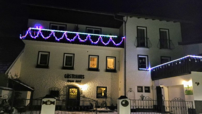 House view at night, © Józef Swierkot An illuminated guest house at night decorated with colorful fairy lights.