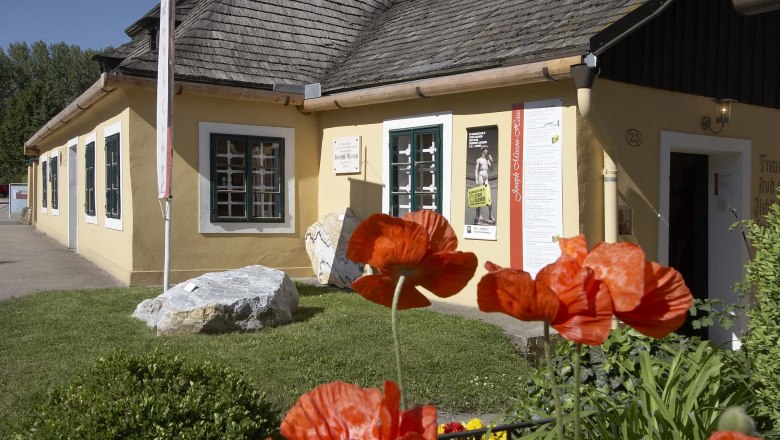 Joseph Misson House, © Gemeinde Hohenwarth-Mühlbach a.M. Yellow house with shingle roof and poppies in the foreground.