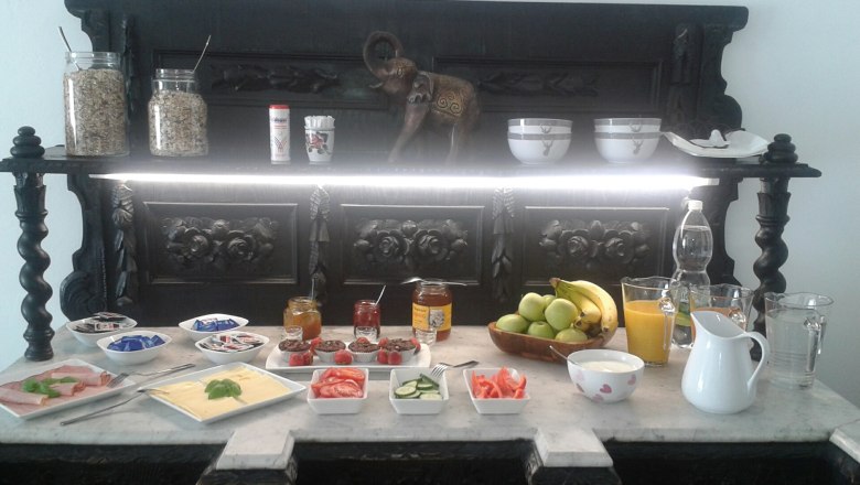 Breakfast room, © Ullram Breakfast buffet with fruit, cold cuts, cheese, jam and drinks on a decorative table.