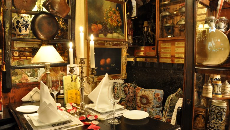 Marchfelderhof, © Gault Millau Comfortably decorated table in a rustic restaurant with candlesticks, pictures and antique objects.