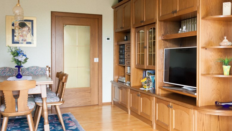 Living room, © Fam. Sulzbacher Comfortable living room with wooden furniture, dining table, chairs and a large cupboard with TV.
