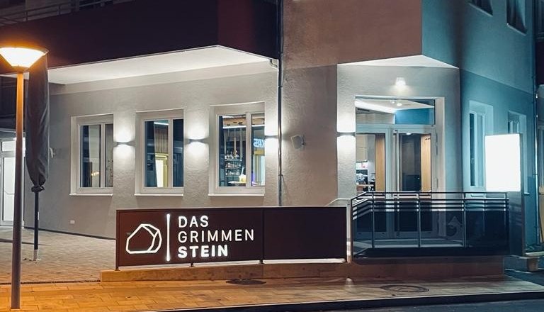 The GrimmenStein exterior, © Das GrimmenStein Exterior view of an illuminated building at night with the sign 'Das GrimmenStein'.