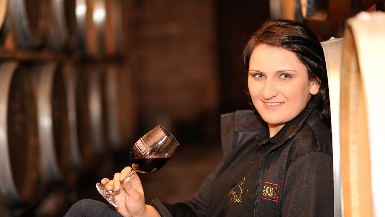 Winemaker Petra Ipsmiller, © Weingut Ipsmiller Woman with wine glass in a wine cellar.