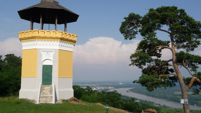 Donauwarte Egelsee, © www.oetk.at A yellow observation tower with a dark roof stands on a hill with a view of the Danube river and a town in the background.