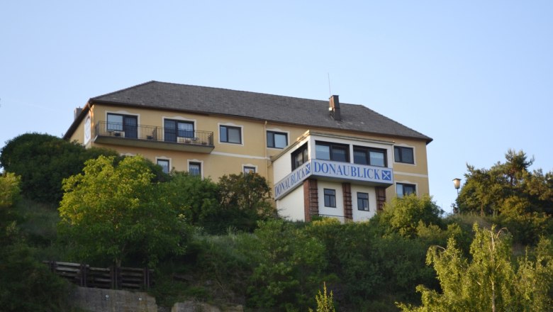 Exterior view3, © Gasthof Donaublick Yellow building with the inscription 'DONAU-BLICK' on a hill surrounded by trees.