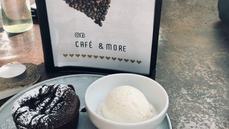 Cafe Herzstück, © Cafe Herzstück_Stephanie Kirschner A dessert plate with chocolate cake, vanilla ice cream and currants next to a centerpiece menu.