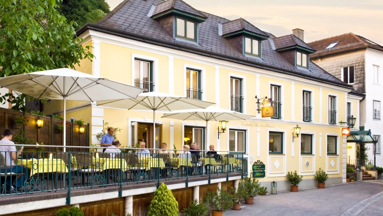 Country inn 'Zur Schönen Wienerin', © Engel A yellow country inn with a terrace and parasols where people are sitting.