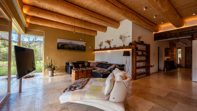 Vacation home by the lake, © Niederösterreich Werbung / Maximilian Pawlikowsky Interior view of a cozy living room with wooden beamed ceiling, large windows and modern furnishings.