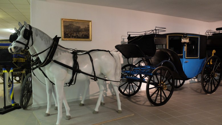 Gala Coupé, © Renate Pokorny A historic carriage with a white horse model in a museum.