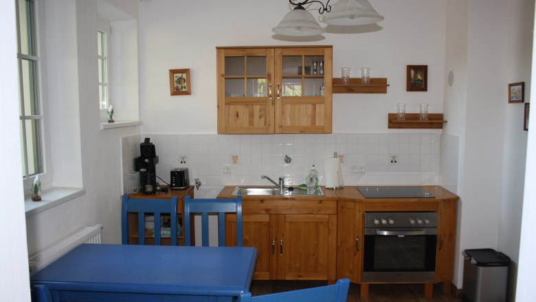 Kitchen in the vacation apartment at Bioweingut Schmidl, © Weingut Schmidl Kitchen in a vacation apartment with wooden furniture, blue chairs and modern equipment.