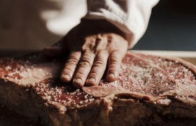 Excellent craftsmanship meets the best meat quality, © Niederösterreich Werbung/Michael Reidinger Close-up of a hand sprinkling coarse salt on a large piece of raw meat.