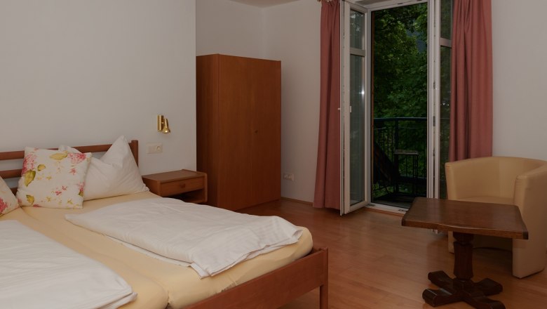 Bedroom, © Landhaus Puchbergerhof by smc Bedroom with double bed, wardrobe, table and chair, window with curtains.