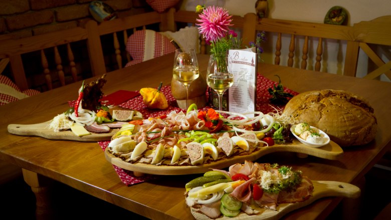 Heurigen snack, © Oberaigner A table with a Heurigen snack: cold cuts, cheese, bread and wine.