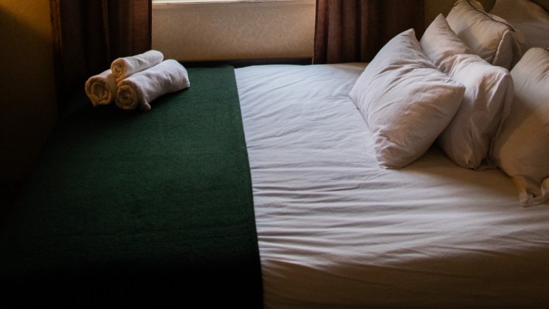 Orlet on the Rax, © Sofia Orlet A cozy bedroom with a bed in front of a window. Outside you can see trees and the roof of a house.