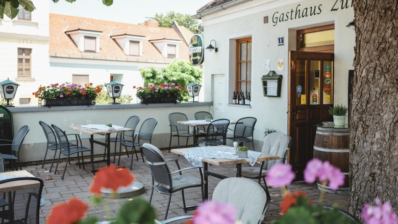 Shady guest garden in Zistersdorf, © Niederösterreich Werbung/Michael Reidinger Shady garden with tables and chairs in front of a restaurant.