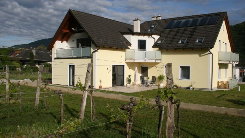 Guest room Auer, © Gerhard Auer Yellow house with balcony and garden, surrounded by vines.