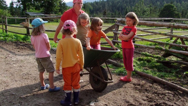There's never a dull moment on the farm!, © zVg Children playing with a wheelbarrow on a farm.