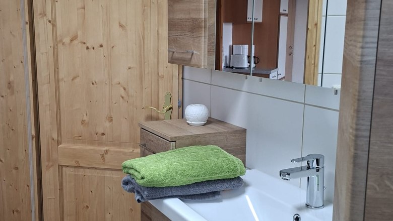 Bathroom, © Ferienwohnung Penz Stolzenthal, Fotograf Hermine Penz Bathroom with wooden cabinets, washbasin and towels.
