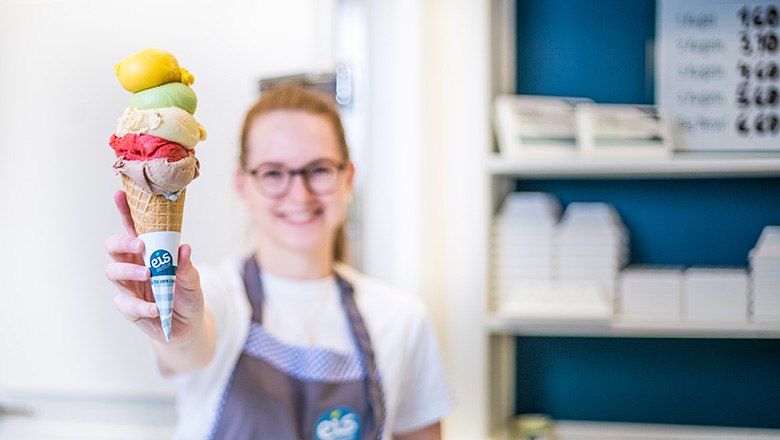 Eis-Greissler farm store ice cream, © Blochberger Eisproduktion GmbH A smiling woman holds an ice cream cone with five different scoops.