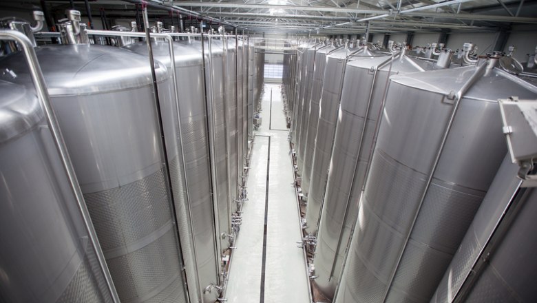 The wine hall, © Markus Kucera Large stainless steel tanks in a modern wine production hall.