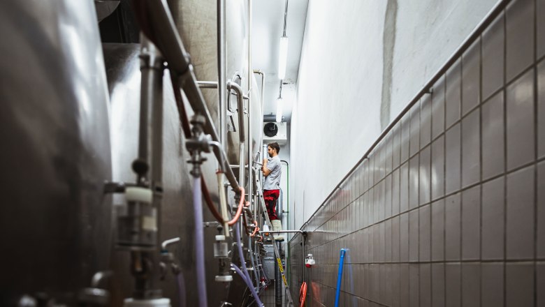 Brewery, © Inge Funke A man works on a brewing kettle in a brewery.