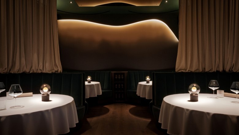 Restaurant, © Laura Thiesbrummel Elegant restaurant with round tables, white tablecloths and subdued lighting.