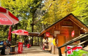 Recharge your batteries on the sun terrace, © Hamari Kletterpark Wooden hut with sunshades and climbing park in the background.