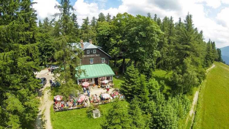 Speckbach hut, © Wiener Alpen, Foto: Franz Zwickl Aerial view of the Speckbacher hut surrounded by trees with terrace and guests.