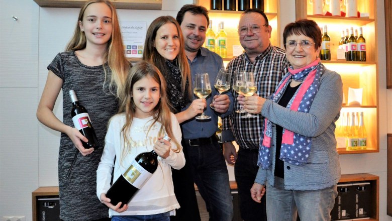 Viticulture Holzer, © Weinbau Holzer Family with wine bottles and glasses in a wine cellar.