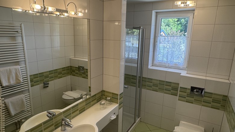 Hotel Zur Alten Schule, © Viregro Capital Gmbh Modern bathroom with green tiles, shower, washbasin and WC.