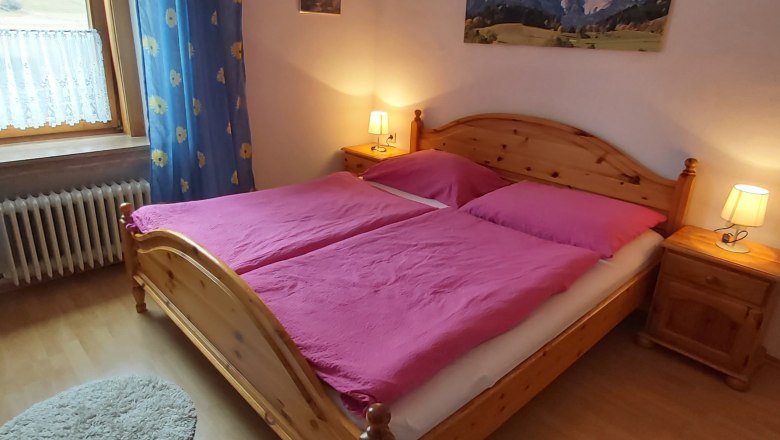 Double room, © Martin Zwinz Cozy double room with wooden bed, pink bed linen and bedside tables with lamps.